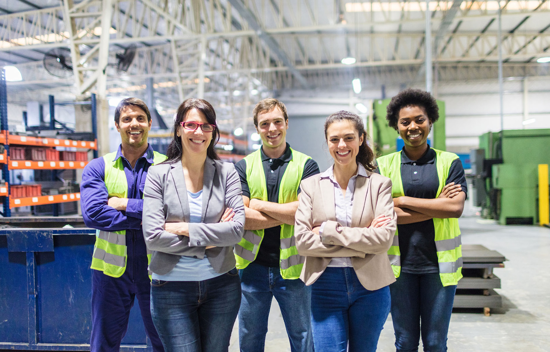 Group portrait of staff at distribution warehouse. Warehouse team standing with arms crossed in factory.